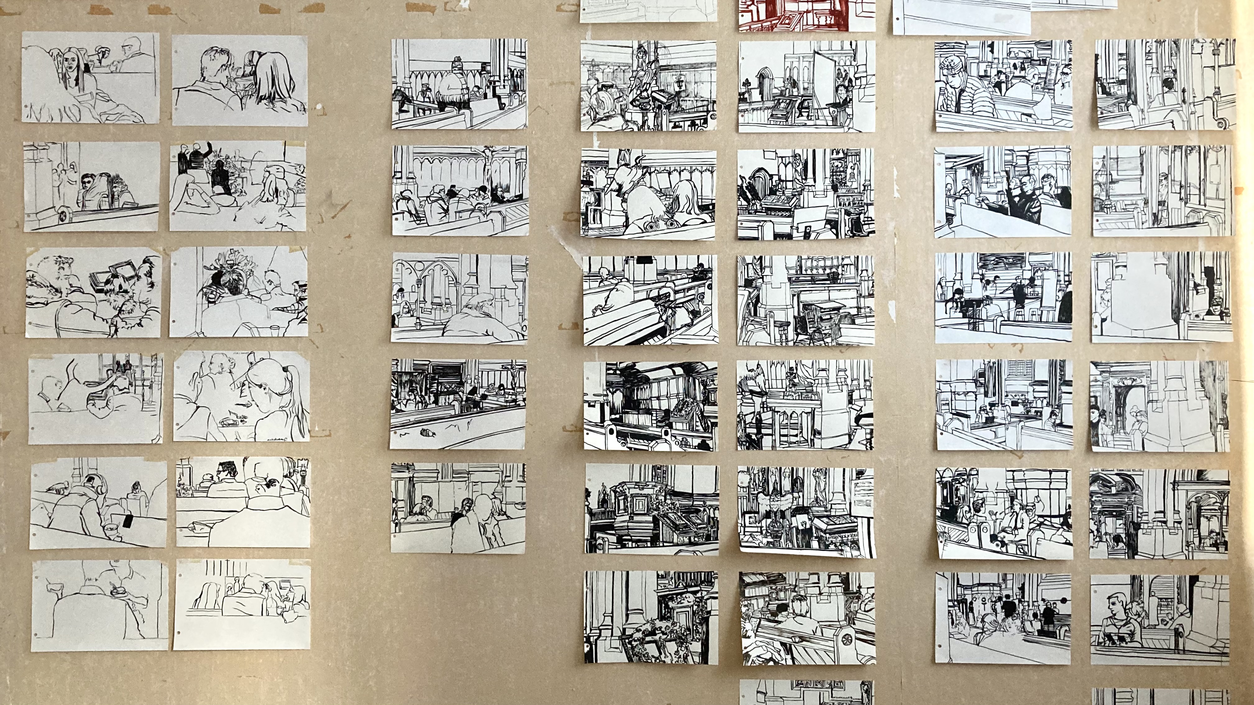 picture of a studio wall with lots of small black and white pen and ink drawings